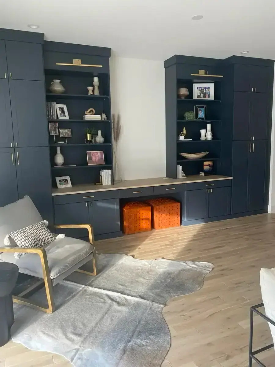 Navy floor-to-ceiling built-in library and desk wall with brass hardware, styled with books and decor